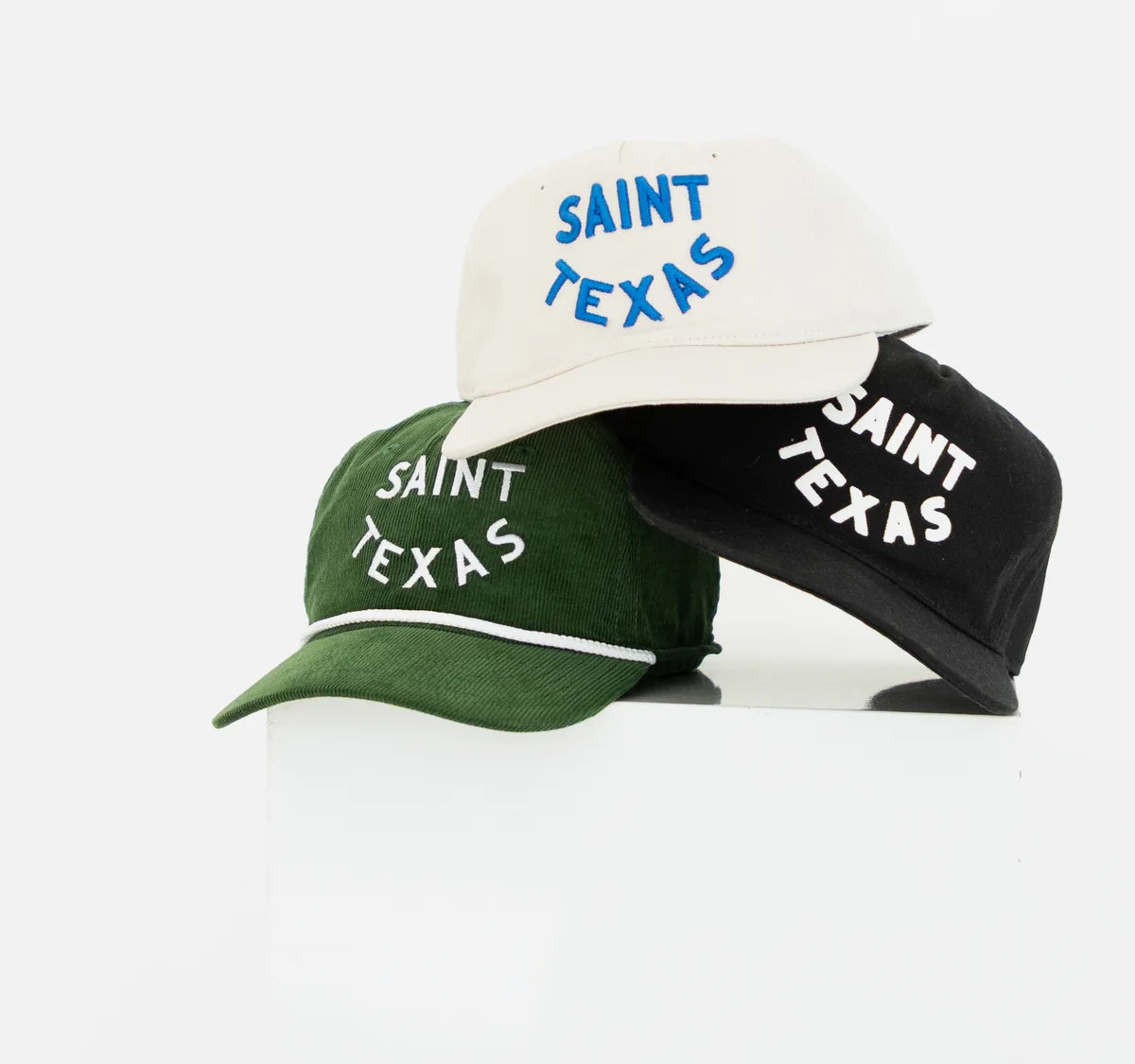 Three Saint Texas caps stacked on a white block